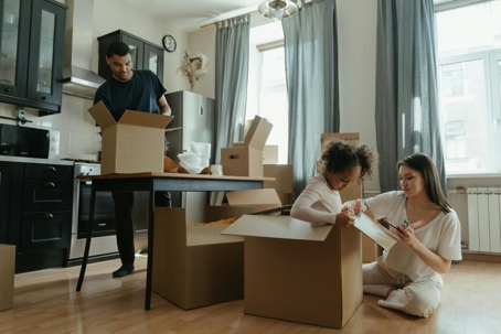 Father is unpacking their things, while mother and child drawing on the cardboard